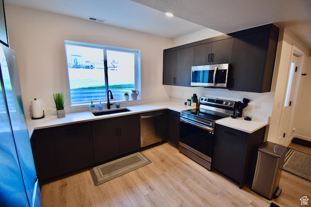 kitchen featuring a sink, visible vents, appliances with stainless steel finishes, and light wood finished floors