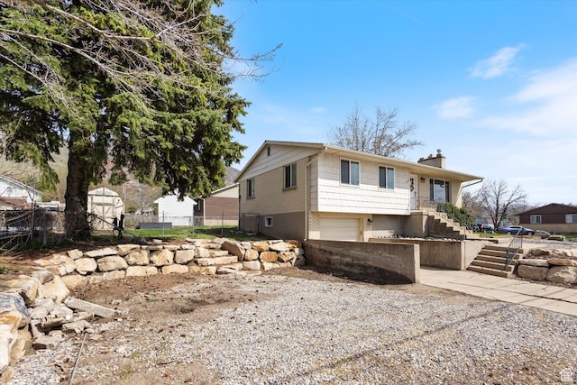 1322 N Main St, Centerville, UT 84014 - exterior space with gravel driveway, fence, stairs, an attached garage, and a chimney