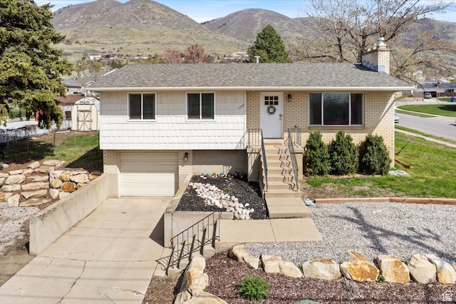 view of front of house featuring a garage, brick siding, a chimney, a mountain view, and driveway