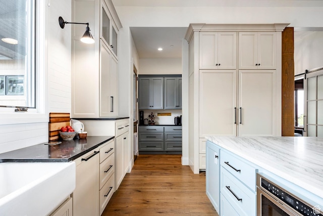 1285 N Oquirrh Mountain Dr, Heber City, UT 84032 - kitchen with dark stone counters, recessed lighting, a barn door, glass insert cabinets, and light wood-type flooring
