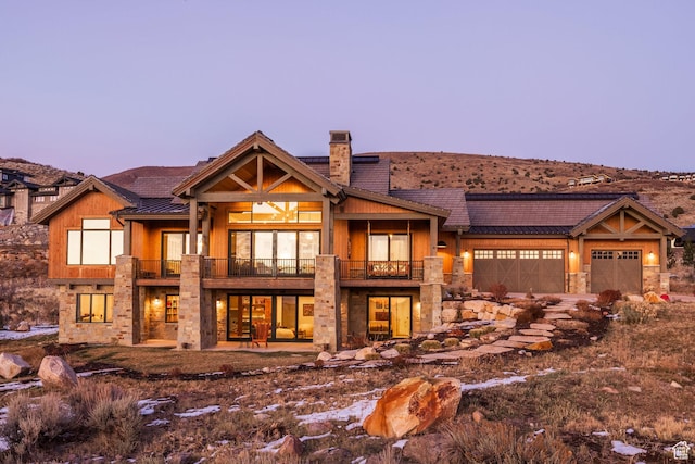 1285 N Oquirrh Mountain Dr, Heber City, UT 84032 - view of front of house featuring a chimney, stone siding, a balcony, and an attached garage
