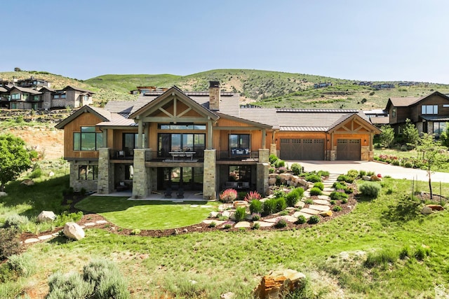 1285 N Oquirrh Mountain Dr, Heber City, UT 84032 - view of front facade with a balcony, a mountain view, stone siding, concrete driveway, and a chimney