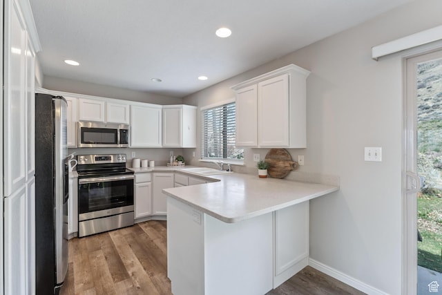 3794 W Morgan Blvd, Cedar Hills, UT 84062 - kitchen featuring white cabinets, a sink, appliances with stainless steel finishes, a peninsula, and light wood finished floors