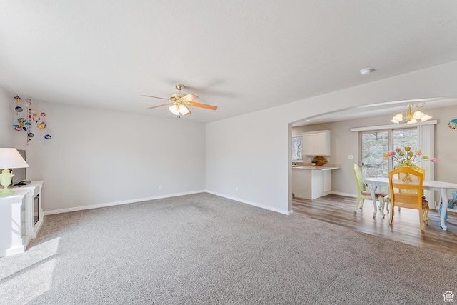 3794 W Morgan Blvd, Cedar Hills, UT 84062 - unfurnished living room featuring baseboards, arched walkways, light colored carpet, and ceiling fan with notable chandelier