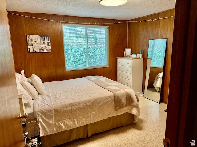 bedroom with carpet flooring and wooden walls