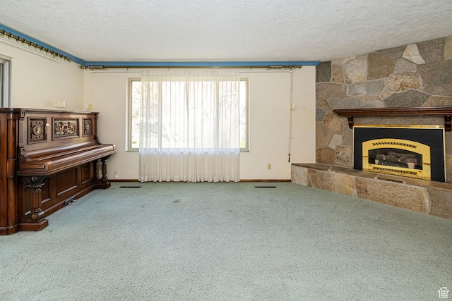 unfurnished living room featuring a textured ceiling, baseboards, carpet, and a stone fireplace