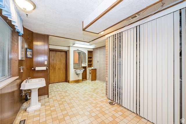 bathroom featuring tile patterned floors, wooden walls, and visible vents
