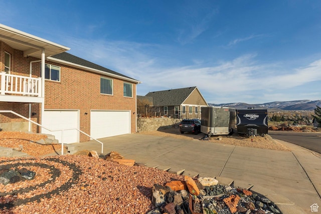 390 Ridge Dr, Heber City, UT 84032 - view of side of home featuring concrete driveway, brick siding, a mountain view, and an attached garage