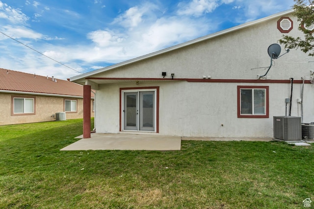 back of property with stucco siding, a patio, a lawn, and central air condition unit