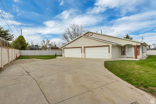 view of side of property featuring a yard, stucco siding, fence, an attached garage, and concrete driveway