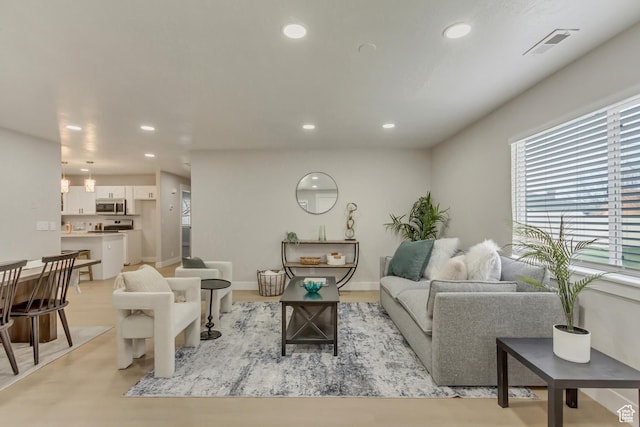 living room featuring visible vents, baseboards, recessed lighting, and light wood-type flooring