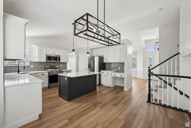 kitchen featuring a sink, light countertops, appliances with stainless steel finishes, white cabinetry, and wood finished floors