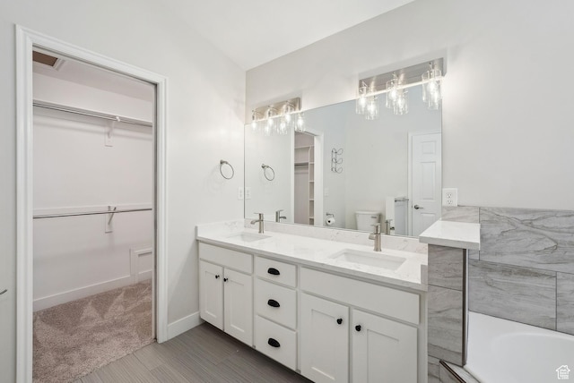 full bathroom featuring double vanity, baseboards, a sink, and toilet