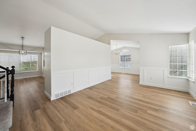 interior space with a chandelier, a healthy amount of sunlight, visible vents, and light wood-style flooring