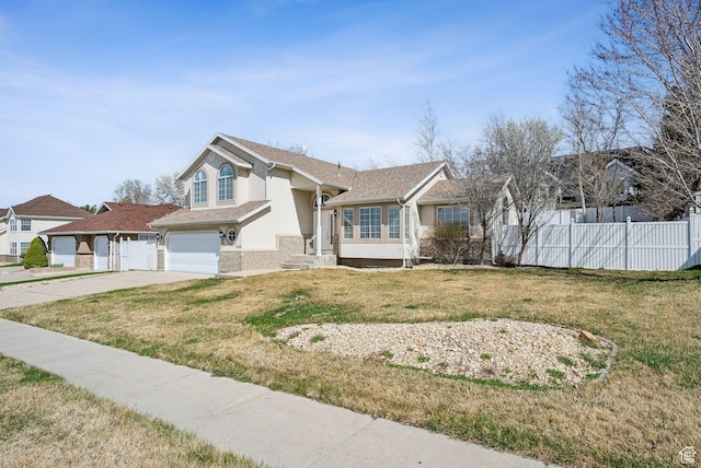 view of front facade with a front yard, a garage, concrete driveway, fence, and stucco siding