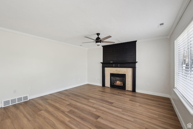 unfurnished living room with visible vents, a ceiling fan, crown molding, and wood finished floors