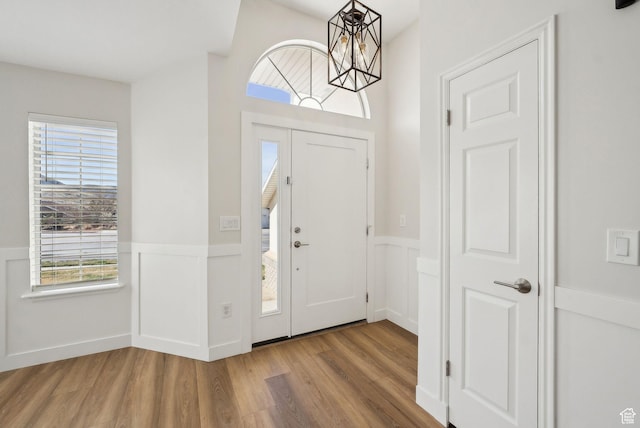 entryway featuring a wainscoted wall, a notable chandelier, and wood finished floors