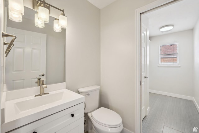 bathroom with toilet, vanity, and baseboards