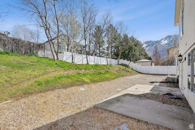 view of yard with a patio area, a fenced backyard, and a mountain view