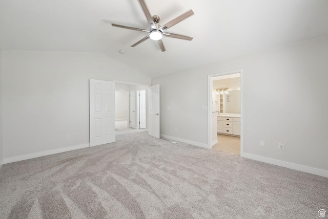 unfurnished bedroom with baseboards, ensuite bathroom, a ceiling fan, lofted ceiling, and light colored carpet