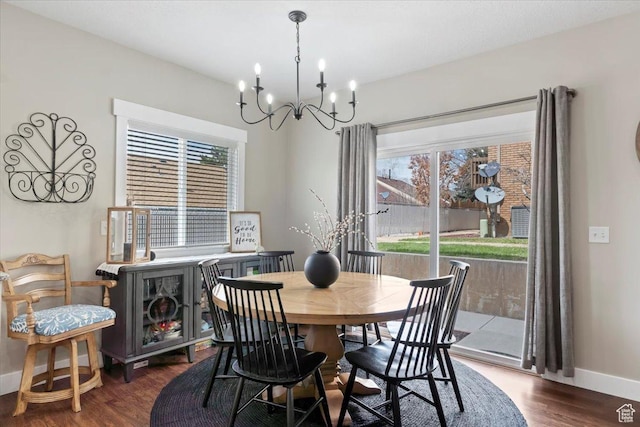 dining space featuring baseboards, plenty of natural light, a chandelier, and wood finished floors