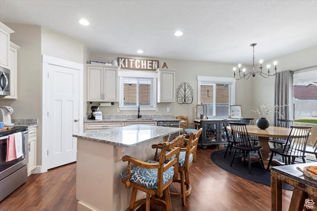 kitchen featuring white cabinetry, a sink, stainless steel appliances, a notable chandelier, and dark wood-style floors
