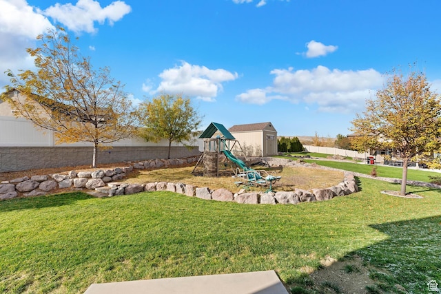 view of playground with an outbuilding, a fenced backyard, a shed, and a lawn