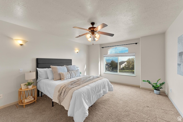 carpeted bedroom featuring baseboards, a textured ceiling, and a ceiling fan