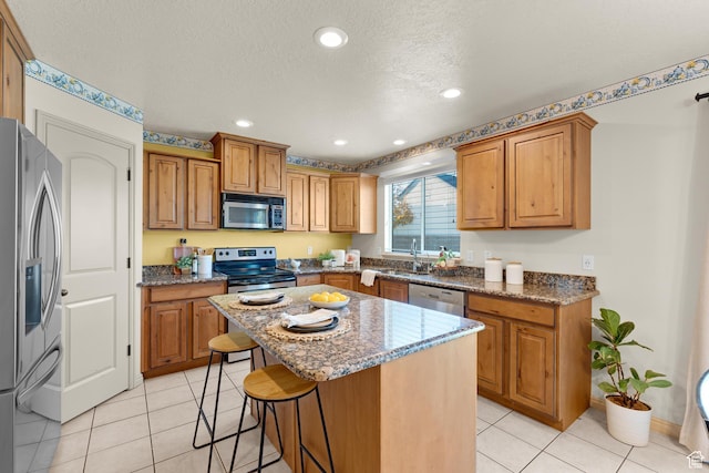 kitchen featuring dark stone countertops, a center island, appliances with stainless steel finishes, and a breakfast bar