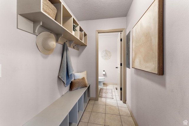 mudroom with light tile patterned floors, baseboards, and a textured ceiling