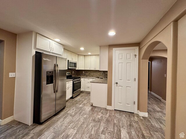 781 N Sherwood Dr, Layton, UT 84041 - kitchen with white cabinets, wood finished floors, a sink, stainless steel appliances, and backsplash