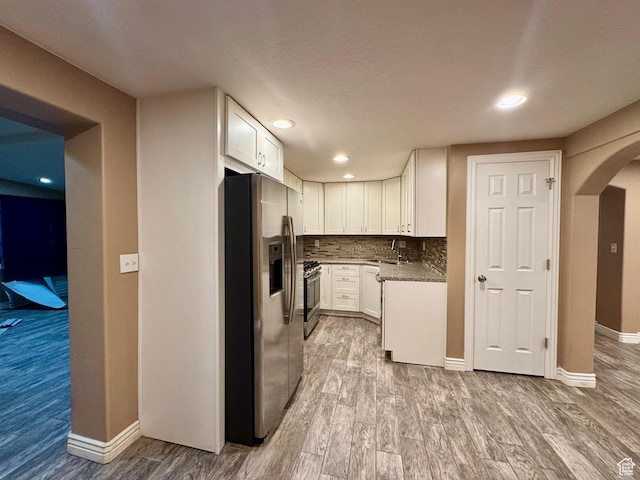 781 N Sherwood Dr, Layton, UT 84041 - kitchen with tasteful backsplash, white cabinetry, stainless steel appliances, arched walkways, and wood finished floors