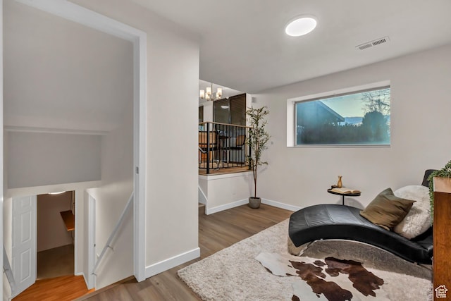 living area with visible vents, baseboards, an upstairs landing, a chandelier, and wood finished floors