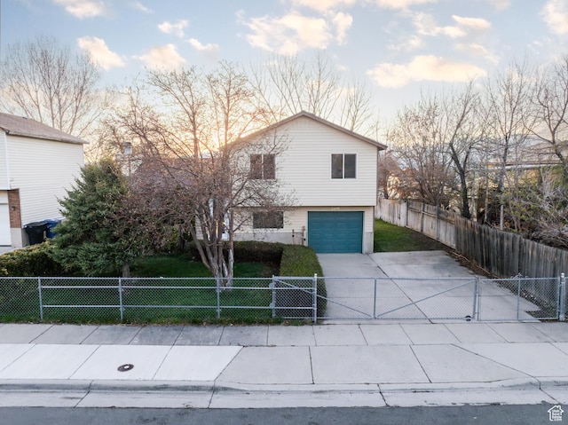 view of front facade with a yard, concrete driveway, a garage, and a fenced front yard