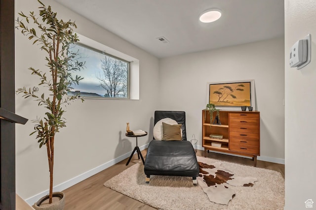 sitting room with wood finished floors, baseboards, and visible vents