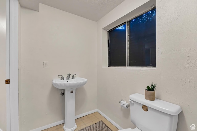bathroom with toilet, tile patterned floors, and baseboards