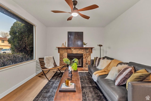 living area with wood finished floors, baseboards, a ceiling fan, and a healthy amount of sunlight
