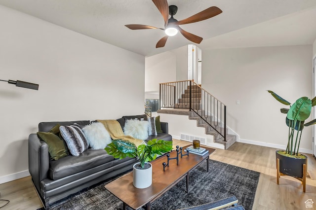 living area with a ceiling fan, visible vents, wood finished floors, stairs, and baseboards