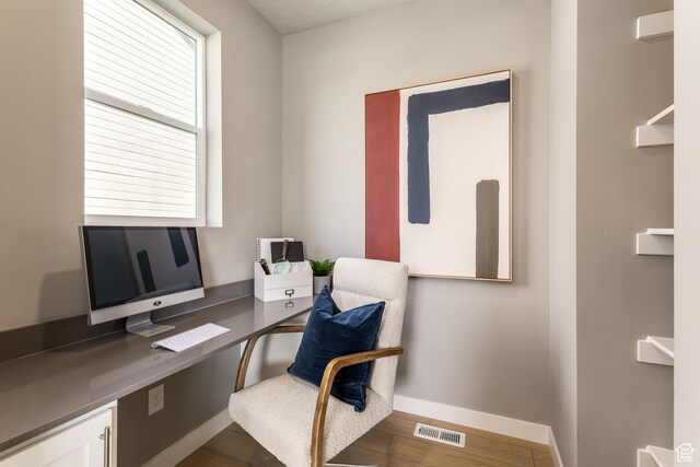 home office featuring visible vents, baseboards, and wood finished floors