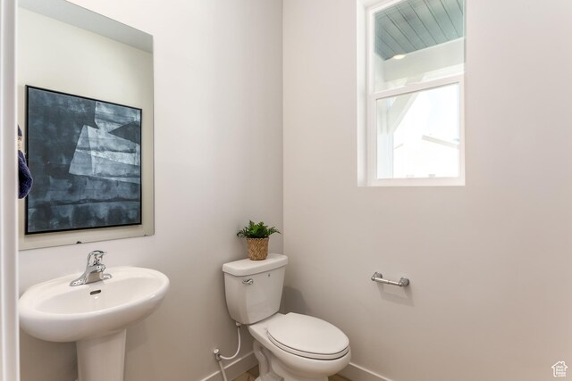 bathroom featuring a sink, toilet, and baseboards