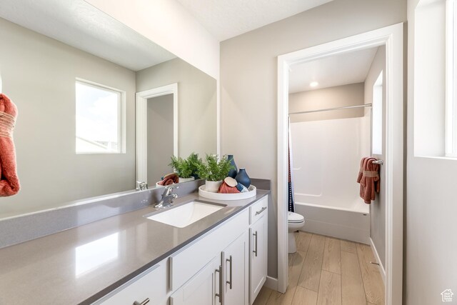 full bathroom featuring toilet, wood finished floors, vanity, and shower / tub combination
