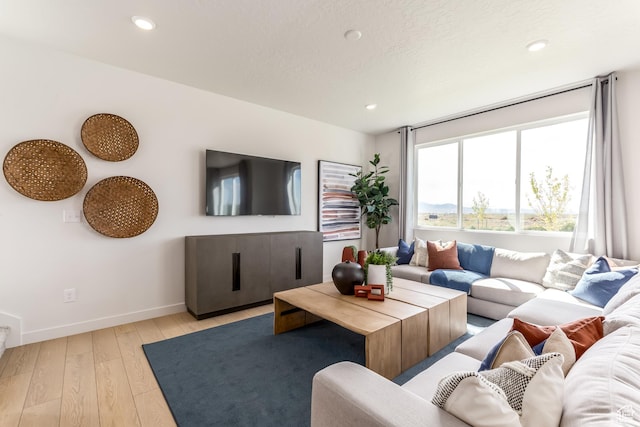 living room with baseboards, recessed lighting, light wood-style floors, and a textured ceiling