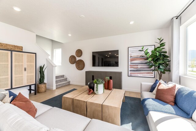 living room featuring plenty of natural light, stairway, and wood finished floors