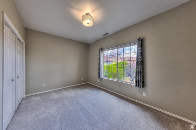 unfurnished bedroom with a closet, baseboards, visible vents, and carpet floors