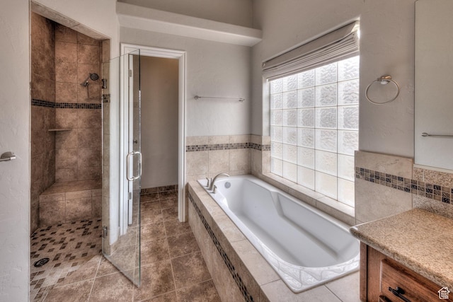 bathroom featuring tile patterned flooring, a bath, a shower stall, and vanity