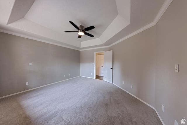 carpeted spare room with baseboards, a ceiling fan, ornamental molding, and a raised ceiling