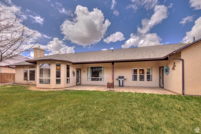 back of property with a patio, stucco siding, a chimney, and a lawn