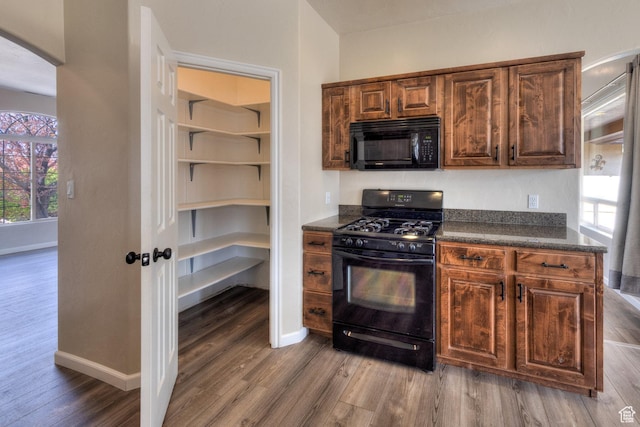 kitchen with baseboards, dark countertops, arched walkways, black appliances, and wood finished floors