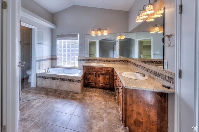 bathroom featuring lofted ceiling, a sink, toilet, double vanity, and a garden tub