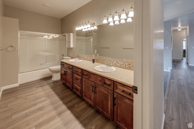 bathroom featuring toilet, wood finished floors, double vanity, and a sink